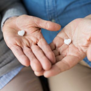close up of couple hands with heart shaped pill