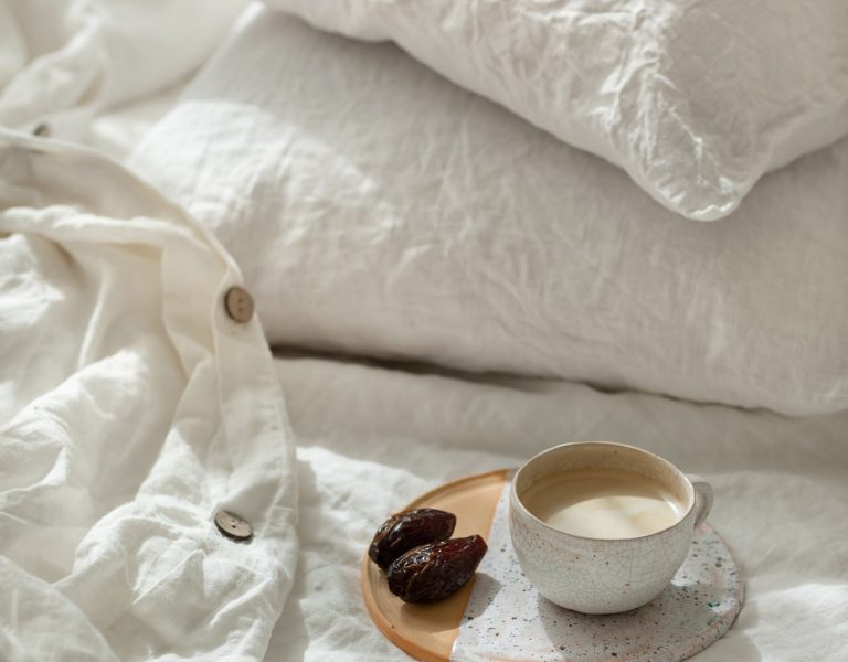 Cup of fresh coffee in bed on ceramic tray, morning mood. Linen cotton textile bedclothes